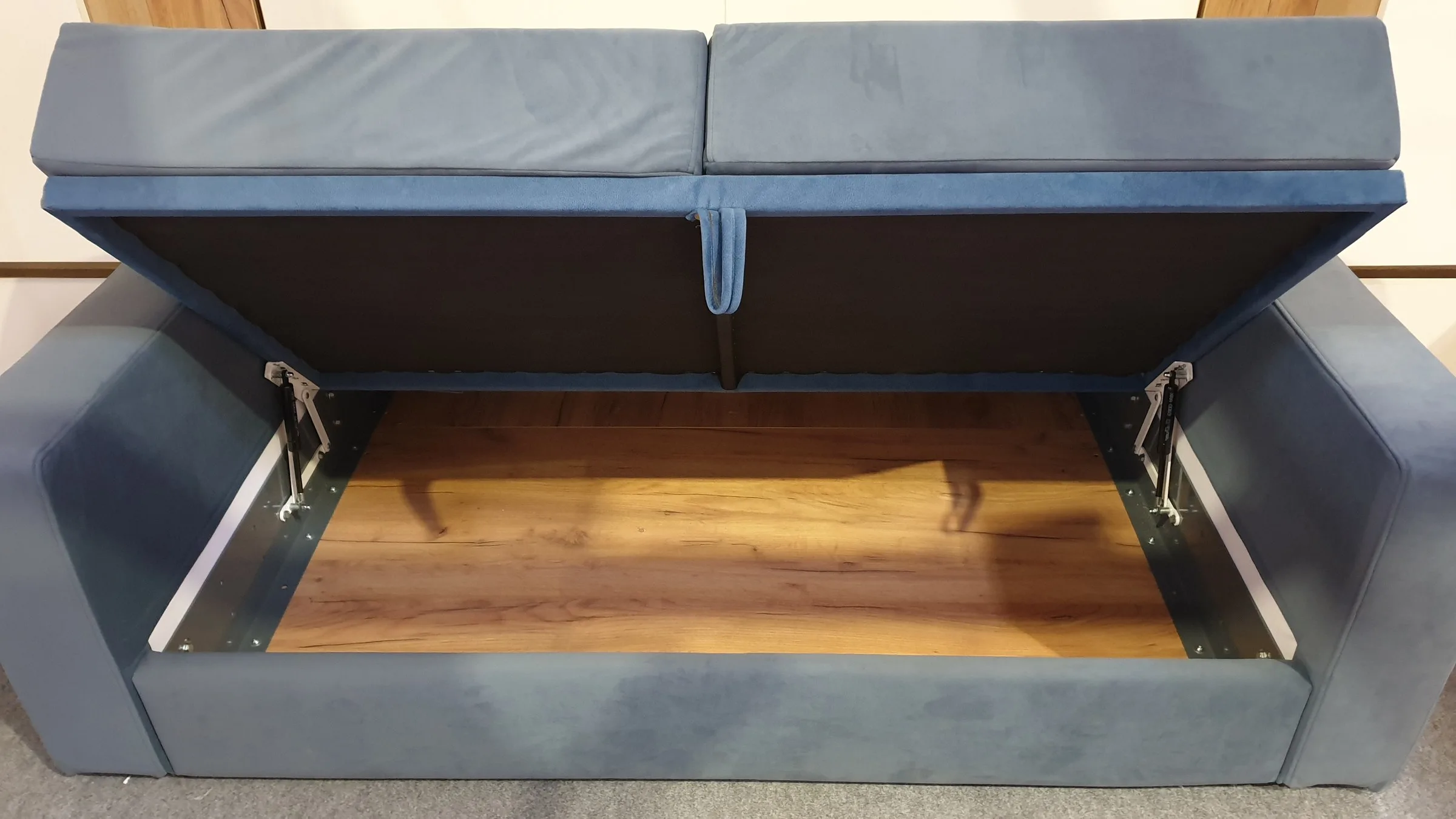 The blue sofa with its seat lifted and the storage box